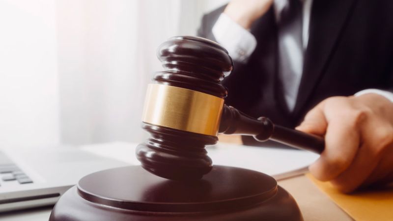 Judge striking gavel, symbolizing legal decisions in a courtroom setting.