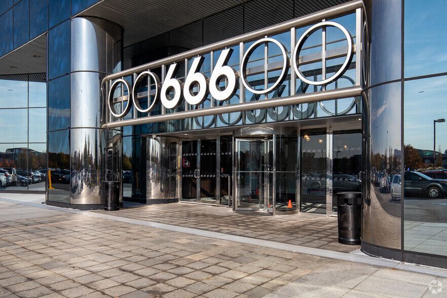 Modern office building entrance with large 666 signage above glass doors on a sunny day.