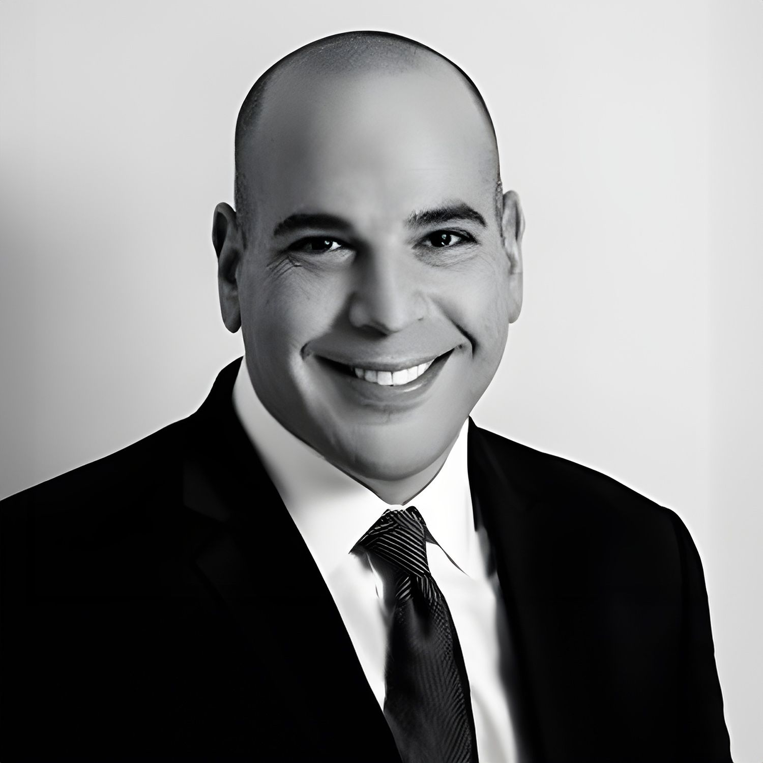 Portrait of a smiling man in a suit and tie, posing against a plain background.